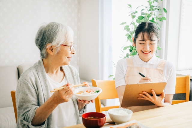 食事をする入居者と記録を取る介護士