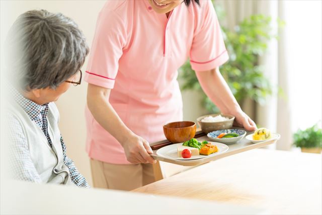 グループホームで食事を運ぶ介護職員