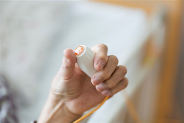 介護施設でコールを押す高齢者